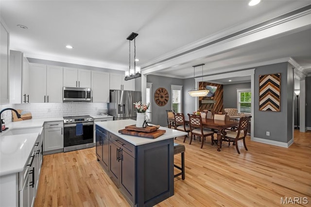 17108 Windsor Crest Blvd, Wildwood, MO 63038 - kitchen featuring ornamental molding, appliances with stainless steel finishes, light countertops, decorative backsplash, and a center island