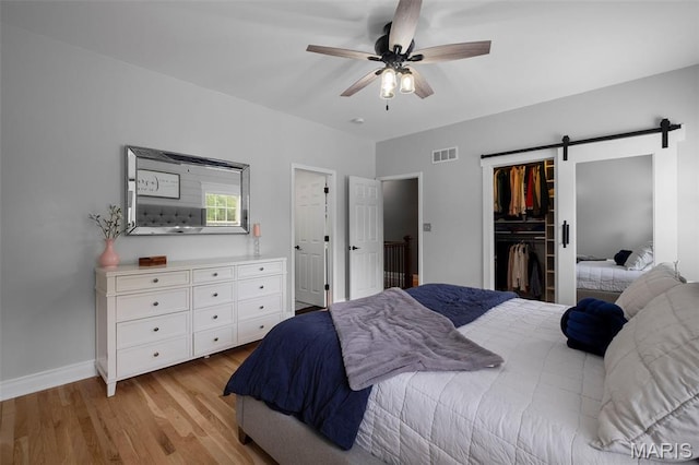 17108 Windsor Crest Blvd, Wildwood, MO 63038 - bedroom with light wood-style floors, a barn door, a walk in closet, and ceiling fan
