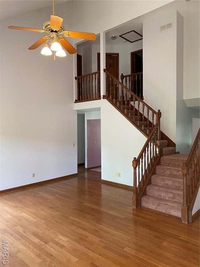 12020 Jacobson Ct, Saint Louis, MO 63044 - unfurnished living room featuring wood finished floors, ceiling fan, stairs, and a towering ceiling