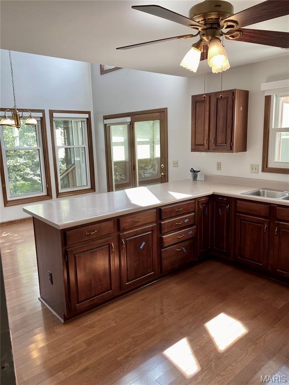 12020 Jacobson Ct, Saint Louis, MO 63044 - kitchen featuring light countertops, a peninsula, wood finished floors, a ceiling fan, and hanging light fixtures