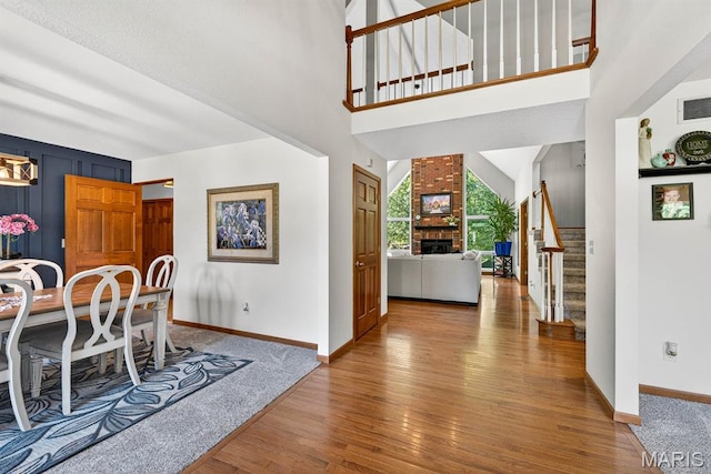 218 W Stonybrook Dr, Ofallon, IL 62269 - entryway with wood finished floors, stairway, a brick fireplace, and a towering ceiling