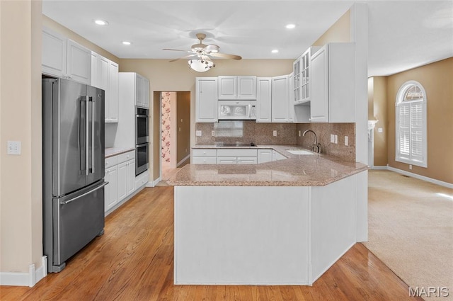 1805 Lincoln Knolls Dr, Edwardsville, IL 62025 - kitchen featuring appliances with stainless steel finishes, a peninsula, ceiling fan, decorative backsplash, and light stone countertops