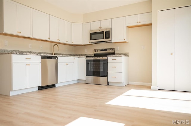 7346 Hazelcrest Dr, Hazelwood, MO 63042 - kitchen with appliances with stainless steel finishes, light wood-style flooring, white cabinets, and light stone counters