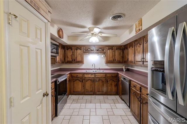 106 Red Bud Cir, Saint Robert, MO 65584 - kitchen featuring stainless steel appliances, ceiling fan, a textured ceiling, light tile patterned floors, and brown cabinets