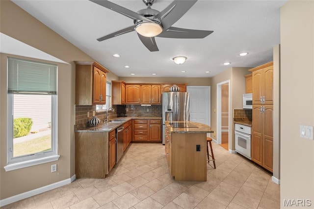2028 During Dr, Arnold, MO 63010 - kitchen with stainless steel appliances, a kitchen breakfast bar, a kitchen island, decorative backsplash, and ceiling fan