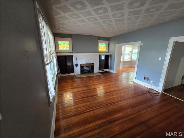 8108 Saint Charles Rock Rd, Saint Louis, MO 63114 - unfurnished living room with a tiled fireplace, wood finished floors, an ornate ceiling, and beverage cooler