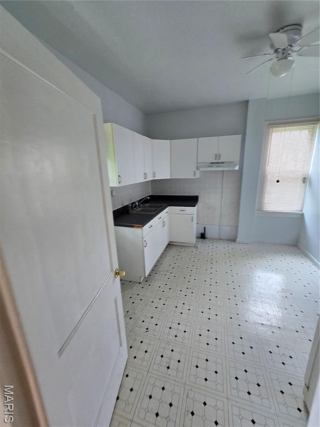 8108 Saint Charles Rock Rd, Saint Louis, MO 63114 - kitchen with under cabinet range hood, ceiling fan, white cabinets, and dark countertops