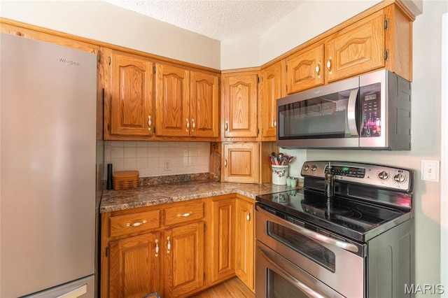 15550 US Highway 63, Rolla, MO 65401 - kitchen with appliances with stainless steel finishes, decorative backsplash, a textured ceiling, brown cabinets, and dark countertops