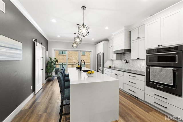 9 E Main St, Washington, MO 63090 - kitchen featuring black appliances, backsplash, a kitchen island with sink, recessed lighting, and a barn door