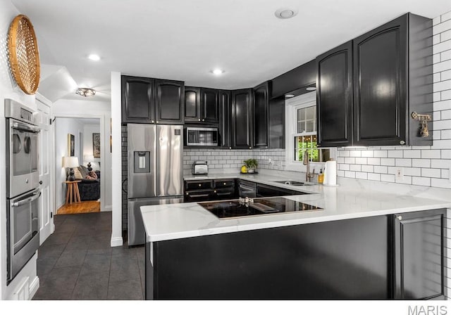 1855 Grassy Ridge Rd, Kirkwood, MO 63122 - kitchen featuring stainless steel appliances, a peninsula, backsplash, dark tile patterned floors, and recessed lighting