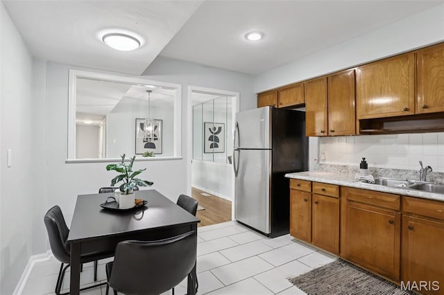520 S Brentwood Blvd Unit 3A, Saint Louis, MO 63105 - kitchen with freestanding refrigerator, brown cabinets, light countertops, decorative backsplash, and light tile patterned floors