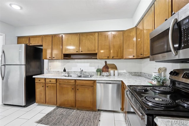 520 S Brentwood Blvd Unit 3A, Saint Louis, MO 63105 - kitchen with stainless steel appliances, brown cabinetry, tasteful backsplash, and light tile patterned floors
