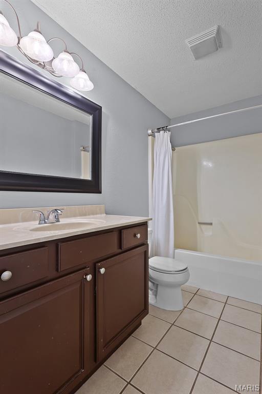 1016 Andra Dr, Maryville, IL 62062 - bathroom with vanity, tile patterned flooring, a textured ceiling, and shower / tub combo