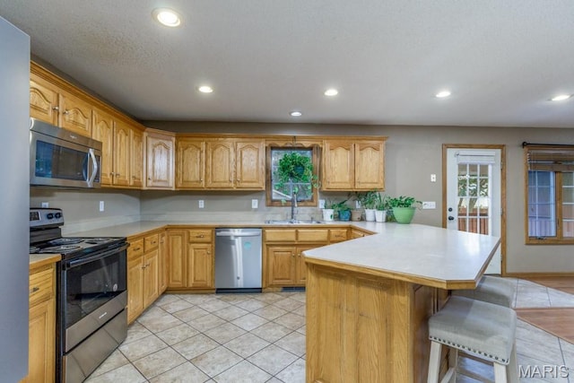 1124 Carpentry Cir, Lebanon, MO 65536 - kitchen featuring appliances with stainless steel finishes, a peninsula, light countertops, a breakfast bar, and recessed lighting