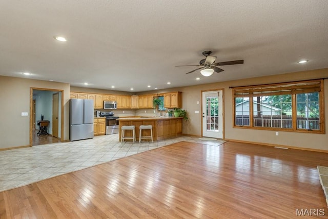 1124 Carpentry Cir, Lebanon, MO 65536 - kitchen featuring stainless steel appliances, light wood-style flooring, a peninsula, a ceiling fan, and open floor plan