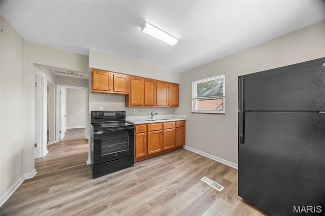 1237 Fairview Ave, University City, MO 63130 - kitchen with black appliances, light countertops, light wood-type flooring, and brown cabinets