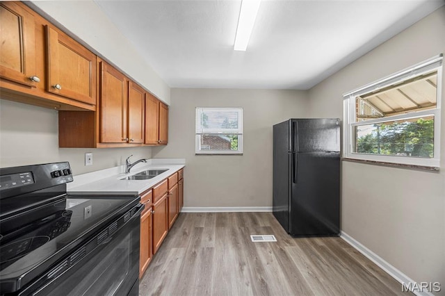 1237 Fairview Ave, University City, MO 63130 - kitchen featuring black appliances, light wood finished floors, brown cabinetry, and plenty of natural light