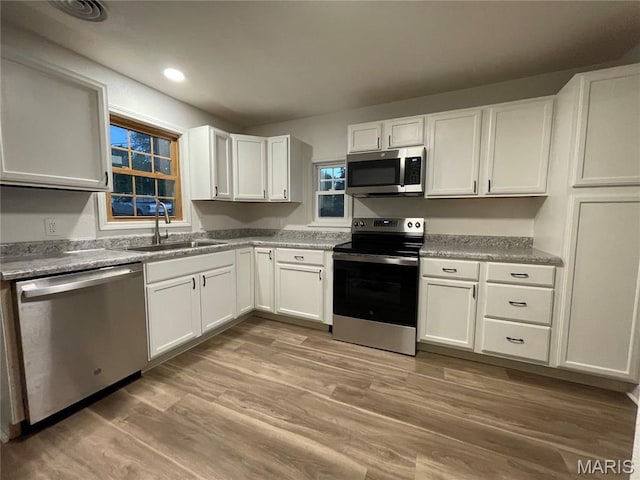 211 N Davis St, Cuba, MO 65453 - kitchen featuring appliances with stainless steel finishes, white cabinets, light wood finished floors, and recessed lighting