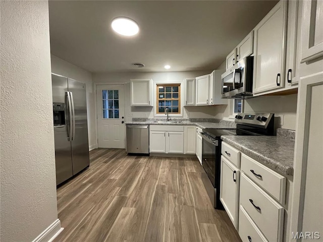 211 N Davis St, Cuba, MO 65453 - kitchen featuring appliances with stainless steel finishes, white cabinets, dark wood-style floors, and a textured wall