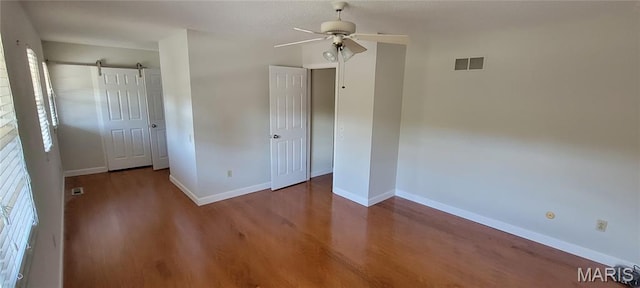 964 Claygate Ct, Ballwin, MO 63021 - unfurnished bedroom featuring a barn door, wood finished floors, and a ceiling fan
