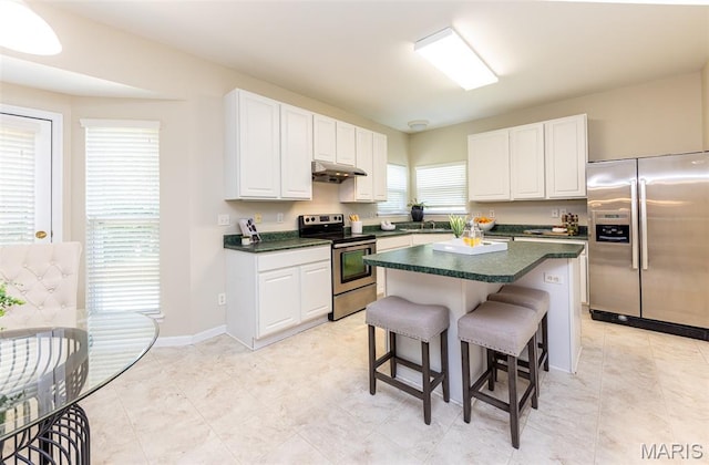 602 Whispering Willows Ct, Ballwin, MO 63021 - kitchen with stainless steel appliances, dark countertops, a kitchen breakfast bar, under cabinet range hood, and white cabinets