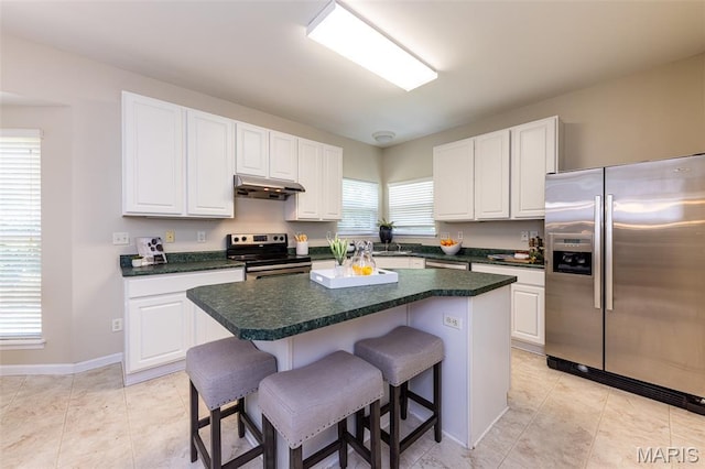 602 Whispering Willows Ct, Ballwin, MO 63021 - kitchen featuring appliances with stainless steel finishes, under cabinet range hood, a kitchen bar, white cabinets, and a center island