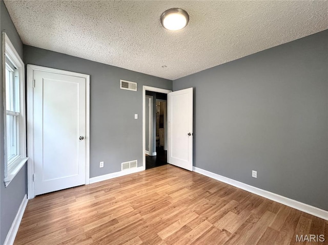 4404 Saint Leo Ln, Saint Ann, MO 63074 - unfurnished bedroom with light wood-style floors and a textured ceiling