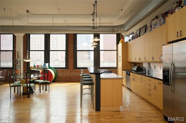 1010 Saint Charles St Unit 802, Saint Louis, MO 63101 - kitchen with appliances with stainless steel finishes, brick wall, light wood-style floors, and a center island