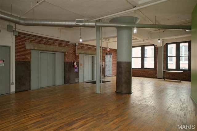 1010 Saint Charles St Unit 802, Saint Louis, MO 63101 - spare room with brick wall, a towering ceiling, wood-type flooring, elevator, and ornate columns
