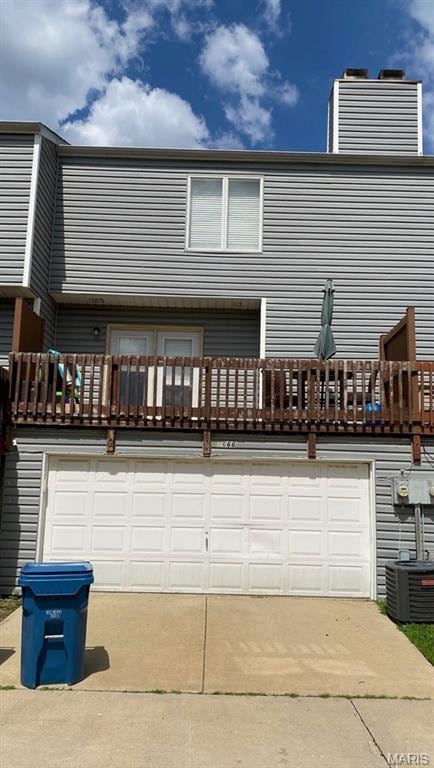 1666 Forest Hills Drive E, Saint Charles, MO 63303 - rear view of property featuring a balcony, driveway, a chimney, and an attached garage
