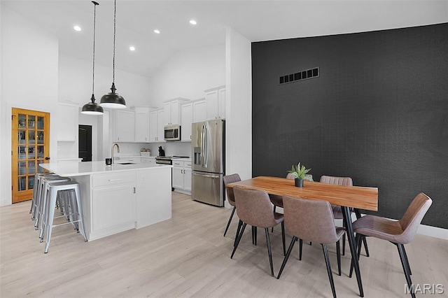 2803 Poolbrook Way, Washington, MO 63090 - kitchen featuring appliances with stainless steel finishes, high vaulted ceiling, light wood-style floors, white cabinets, and a center island with sink