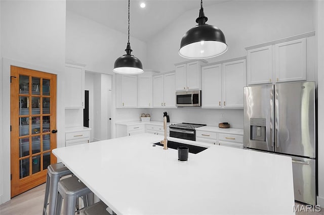 2803 Poolbrook Way, Washington, MO 63090 - kitchen featuring stainless steel appliances, high vaulted ceiling, white cabinets, an island with sink, and decorative light fixtures