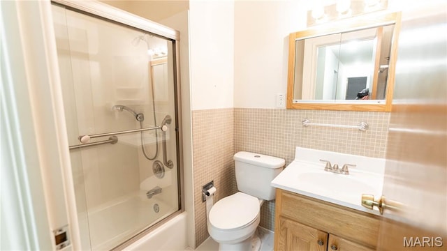 2480 Cambridge Dr, Florissant, MO 63033 - bathroom featuring tile walls, vanity, a wainscoted wall, and bath / shower combo with glass door