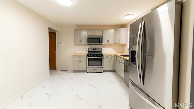 2480 Cambridge Dr, Florissant, MO 63033 - kitchen with appliances with stainless steel finishes, gray cabinets, light marble finish flooring, and backsplash