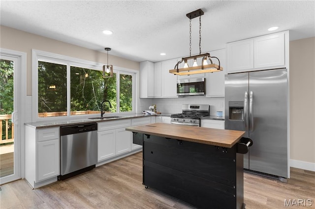 1618 Clock Tower Dr, Saint Louis, MO 63138 - kitchen with stainless steel appliances, butcher block counters, backsplash, light wood finished floors, and pendant lighting