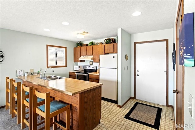 40 Robinwood Unit 2C, Lake Ozark, MO 65049 - kitchen with white appliances, under cabinet range hood, a peninsula, a kitchen bar, and a textured ceiling