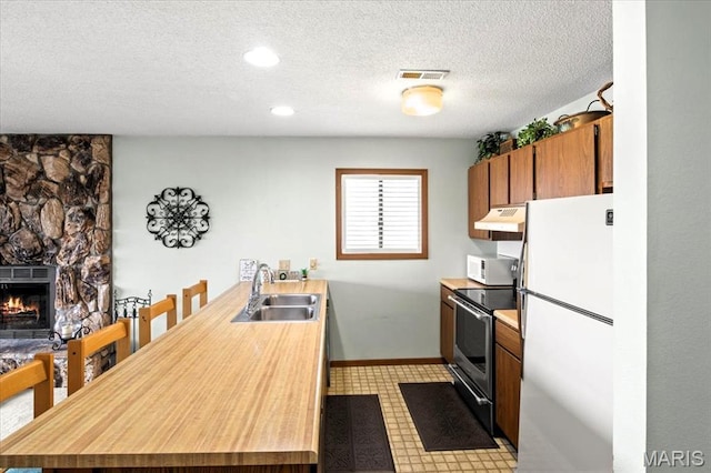 40 Robinwood Unit 2C, Lake Ozark, MO 65049 - kitchen featuring white appliances, under cabinet range hood, a peninsula, a textured ceiling, and brown cabinetry
