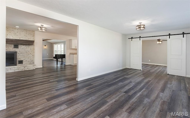 5 Lakeshore Dr, New Baden, IL 62265 - unfurnished living room featuring a barn door, dark wood-style floors, and a brick fireplace