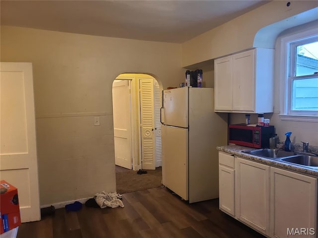 419 Garrison Ave, Cahokia, IL 62206 - kitchen with freestanding refrigerator, stainless steel microwave, white cabinetry, dark wood finished floors, and arched walkways