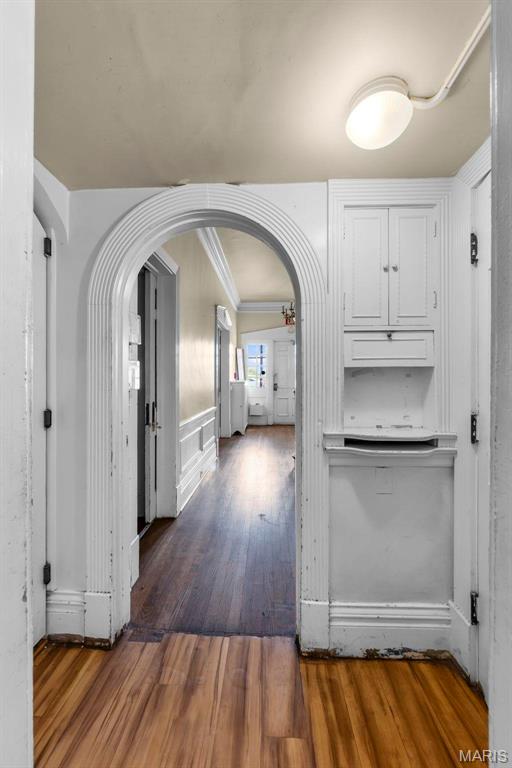 325 N Spring St, Cape Girardeau, MO 63701 - kitchen featuring arched walkways, wood finished floors, white cabinetry, ornamental molding, and light countertops