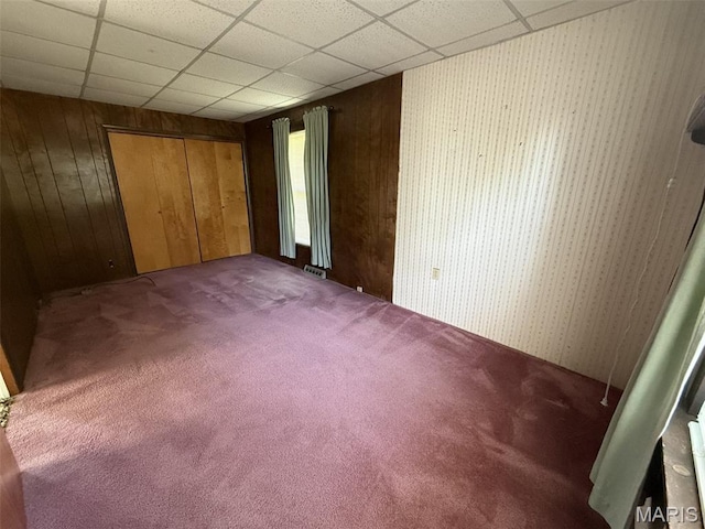 1220 W Edwards St, Vandalia, IL 62471 - unfurnished bedroom featuring carpet floors, wooden walls, a closet, and a paneled ceiling
