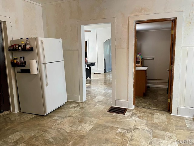 204 E Columbia St, Litchfield, IL 62056 - kitchen featuring freestanding refrigerator, arched walkways, and stone finish floors