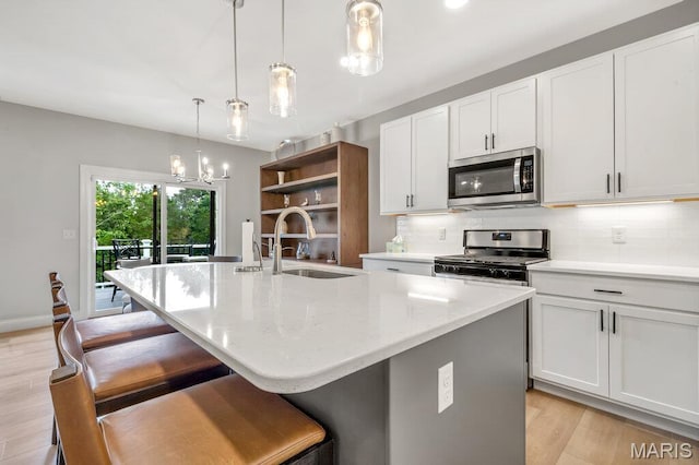 845 Kingston Hills Ct, Fenton, MO 63026 - kitchen with appliances with stainless steel finishes, backsplash, light wood-style flooring, a kitchen island with sink, and white cabinets