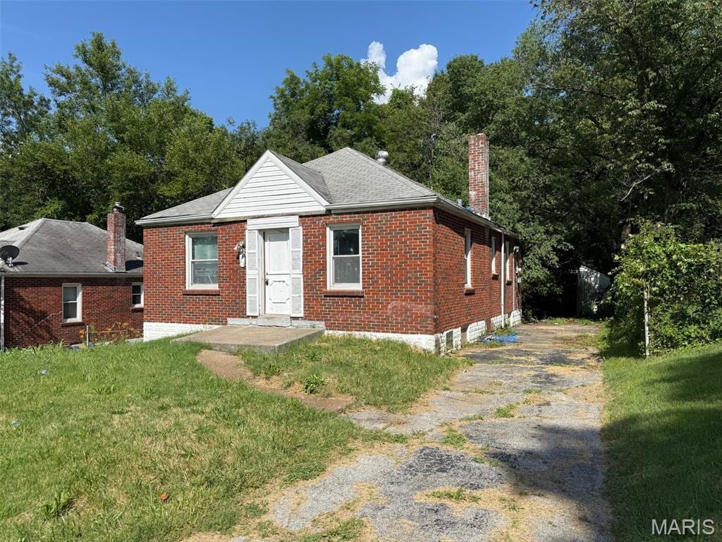 5411 Fletcher St, Jennings, MO 63136 - bungalow-style house featuring a chimney, brick siding, and a front yard
