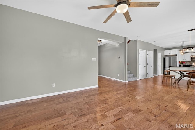 907 Wilderness Way Dr, Eureka, MO 63025 - unfurnished living room with ceiling fan, light wood-style flooring, a chandelier, and stairway