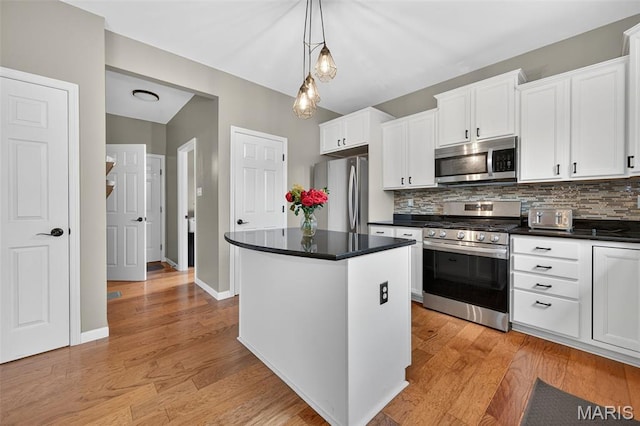 907 Wilderness Way Dr, Eureka, MO 63025 - kitchen featuring stainless steel appliances, a kitchen island, dark countertops, white cabinetry, and backsplash