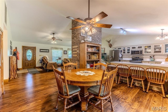 dining room featuring a ceiling fan, vaulted ceiling, wood finished floors, and a chandelier