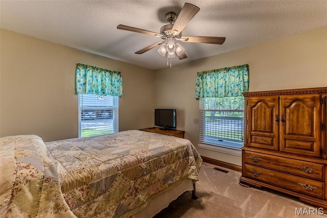 bedroom featuring carpet floors, a ceiling fan, and a textured ceiling