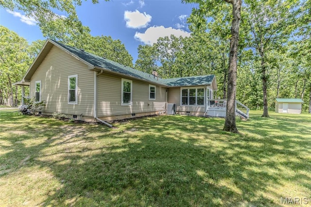 rear view of house featuring a lawn, a chimney, a deck, and roof with shingles