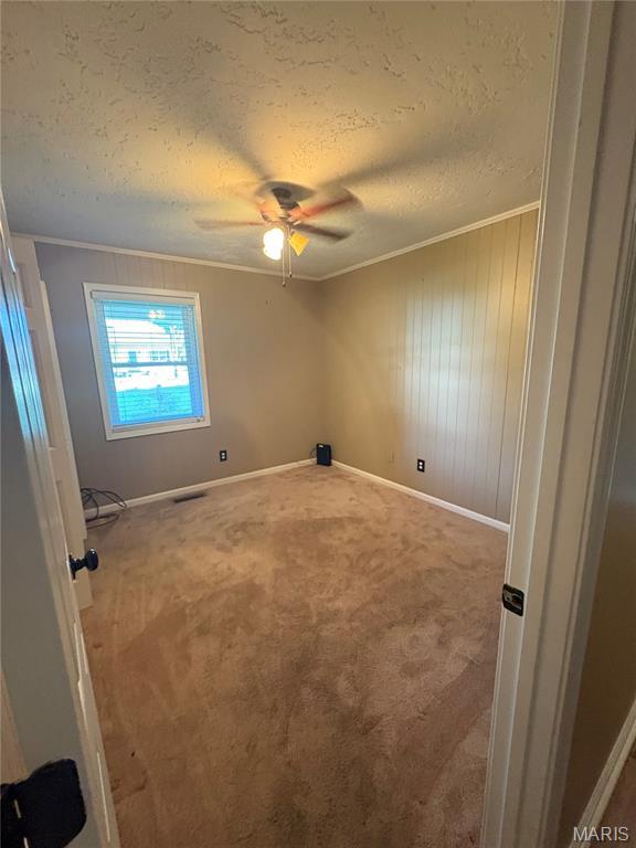 305 Manor, Steele, MO 63877 - carpeted empty room with ornamental molding, ceiling fan, a textured ceiling, and wood walls